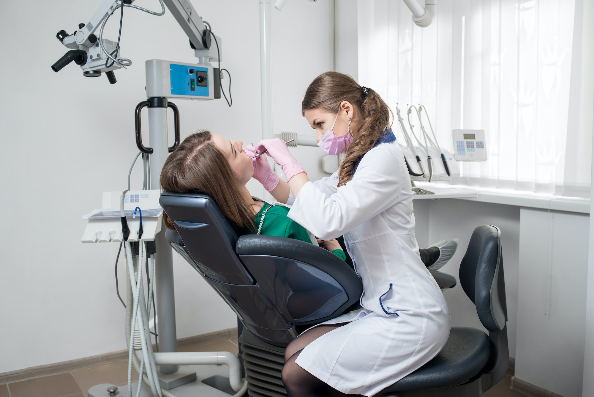 dentist-with-dental-tools-mirror-and-probe-checking-up-patient-teeth-at-dental-clinic-office